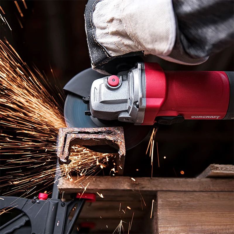 Угловая шлифмашина WORCRAFT AG08-125PS в процессе резки металлического уголка, из-под диска летят искры.