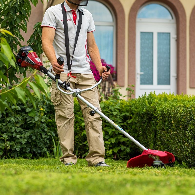 Мужчина косит траву триммером