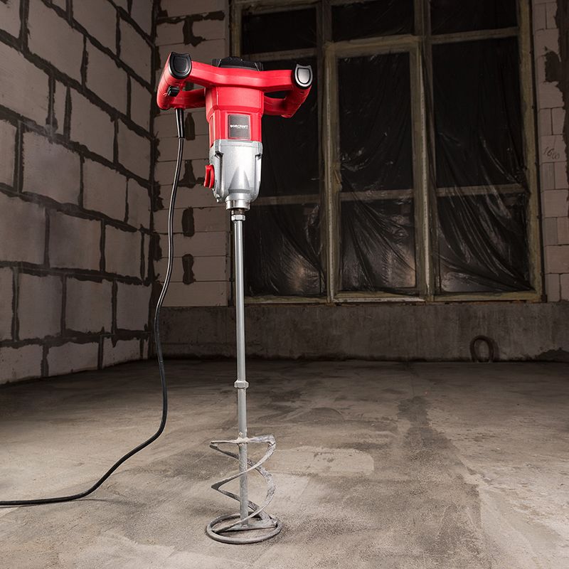 Працівник використовує будівельний міксер WORCRAFT EM14-140 на бетонній підлозі в будівельному приміщенні.