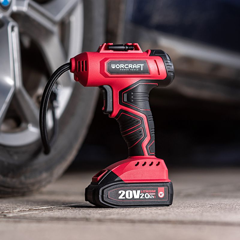 Аккумуляторный компрессор WORCRAFT CAC-S20LiG рядом с колесом автомобиля.