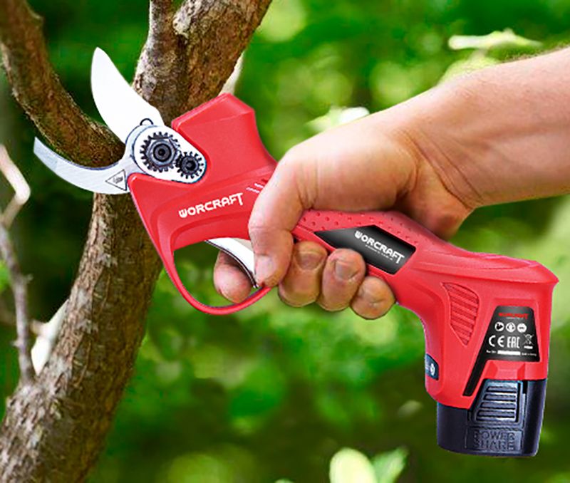 Аккумуляторный секатор WORCRAFT CSC-16LiB в действии, обрезает ветку дерева.
