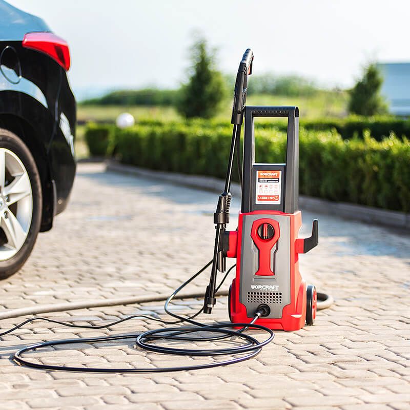 Мойка высокого давления WORCRAFT HC16-90 рядом с автомобилем на стоянке.