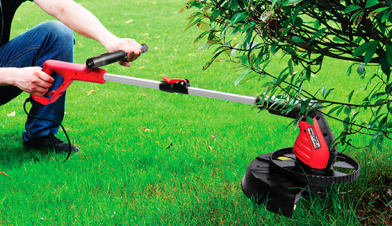 Подрезка травы электрическим триммером WORCRAFT EGT07-300 под кустами.