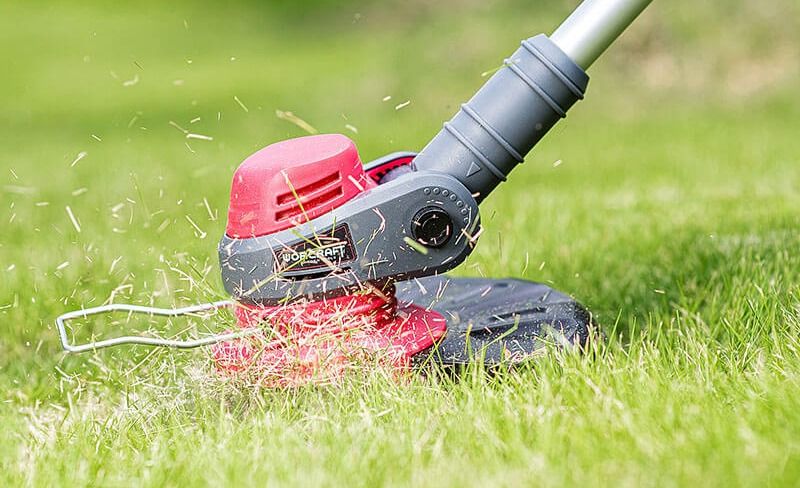 Близкий план режущей головки триммера WORCRAFT CGT-S20LiD в процессе скашивания травы.