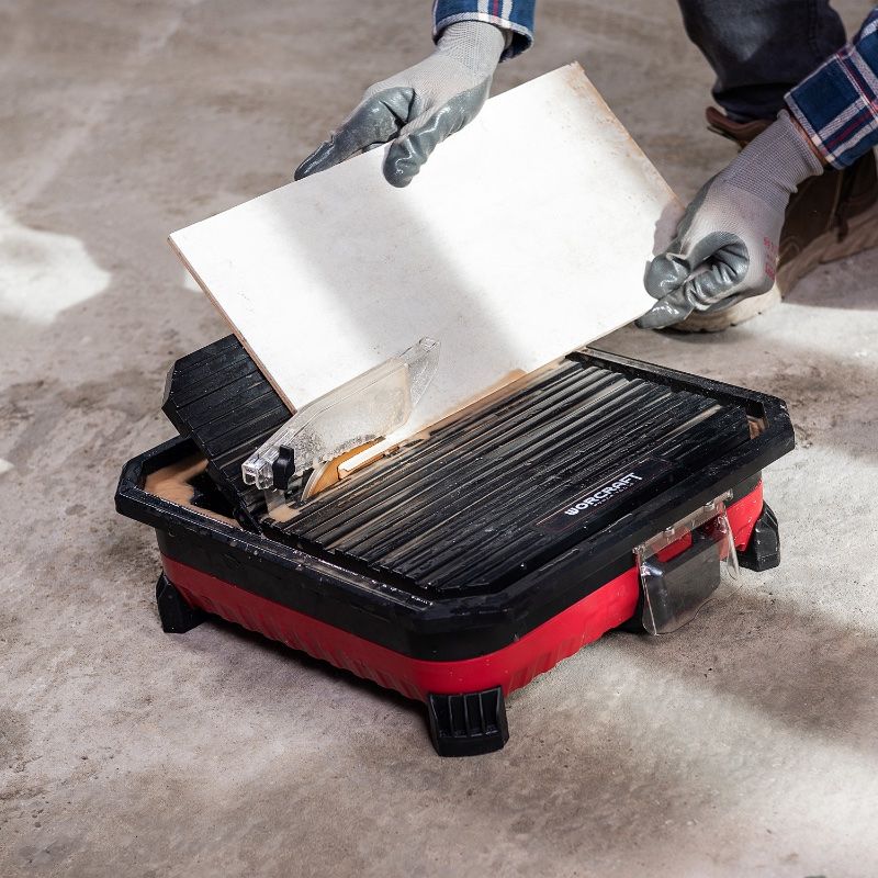 Мастер аккуратно опускает плитку к диску аккумуляторного плиткореза WORCRAFT CTS-S20Li.