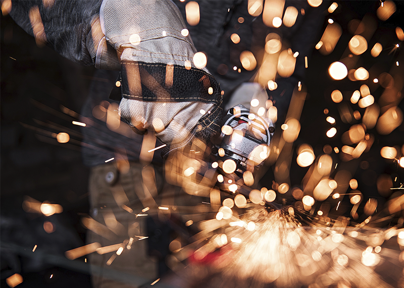 Угловая шлифмашина WORCRAFT активно шлифует металл, вокруг много искр.