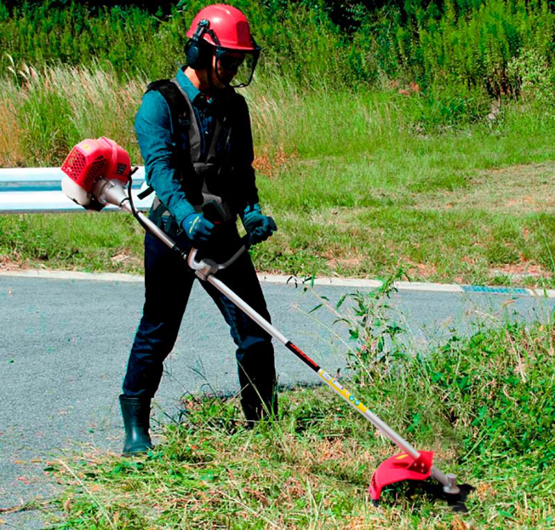 Мотокоса WORCRAFT WGT52-280 в действии на обочине дороги.