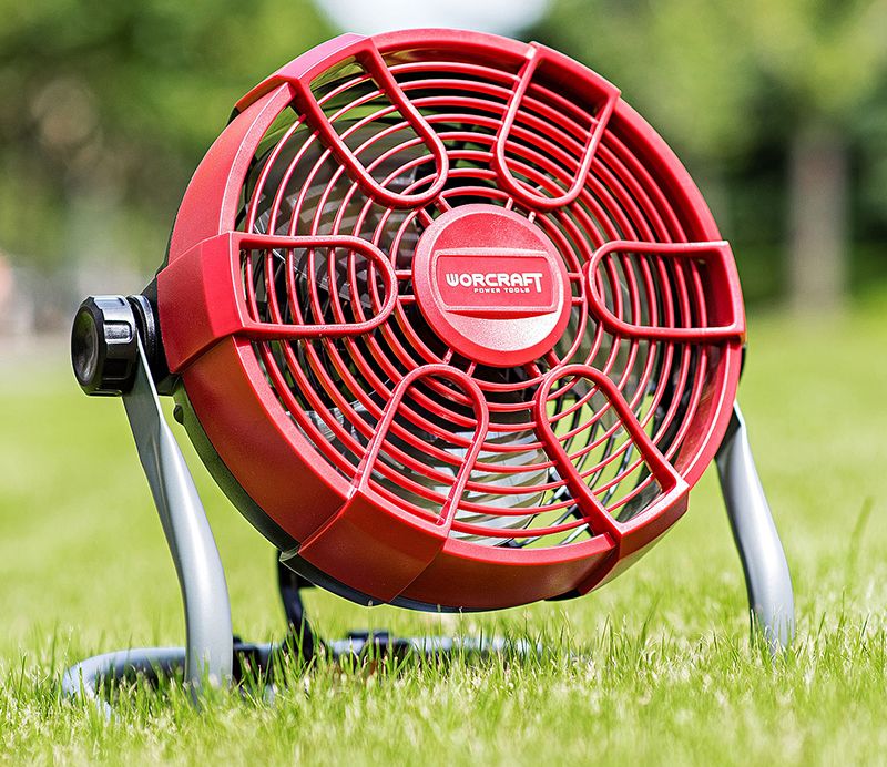 Вентилятор WORCRAFT CJF-S20Li на аккумуляторе установлен на траве в саду.