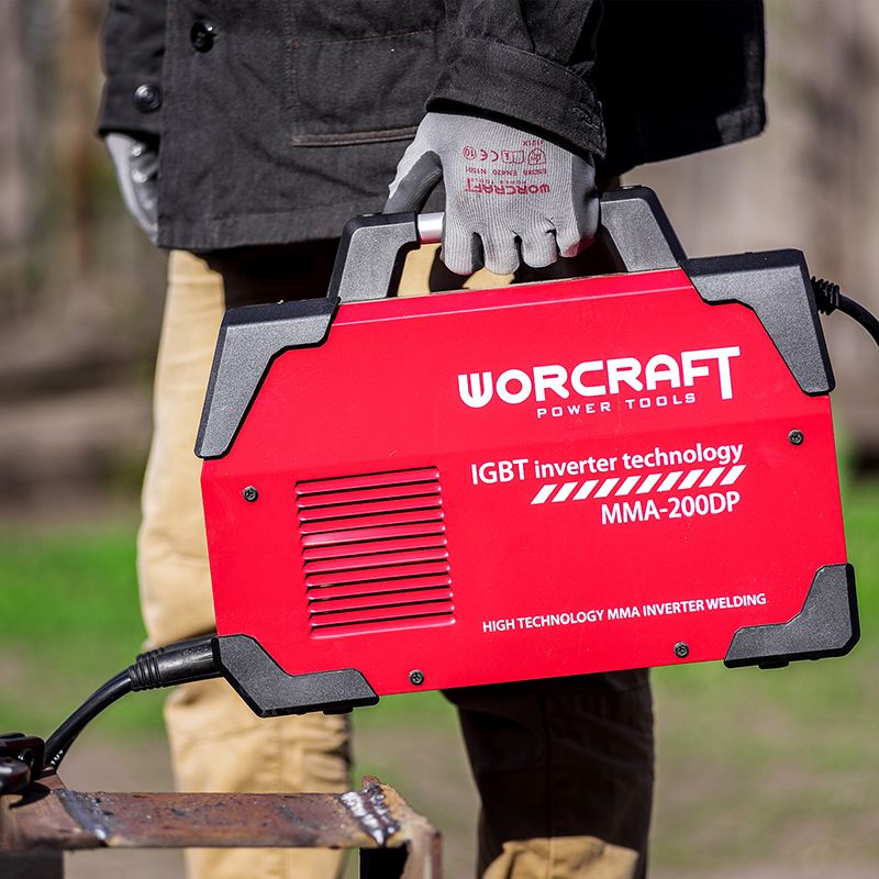 Мужчина держит сварочный аппарат WORCRAFT MMA-200DP за ручку.