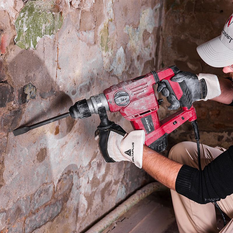 Мастер работает перфоратором WORCRAFT RH15-32X, выполняя демонтаж старой штукатурки.